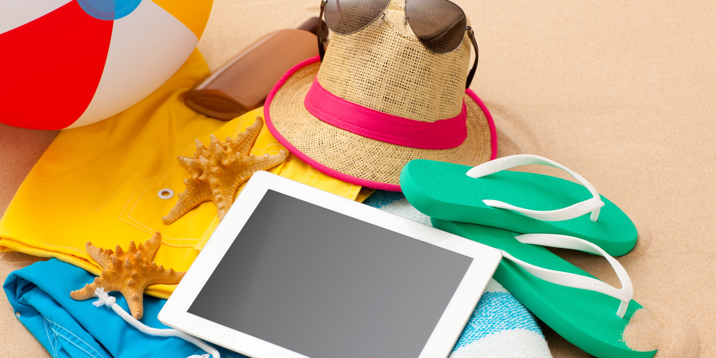 Flat lay com itens essenciais como protetor solar, óculos de sol, chapéu e power bank.